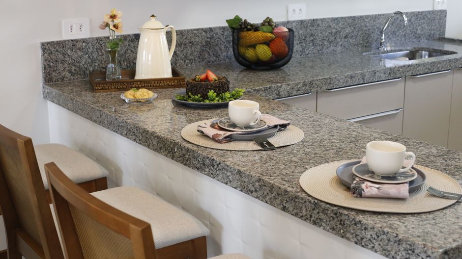 A kitchen counter with a polished stone top and two place settings.
