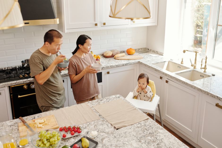 A family kitchen with a stone countertop and a dining table beside it.